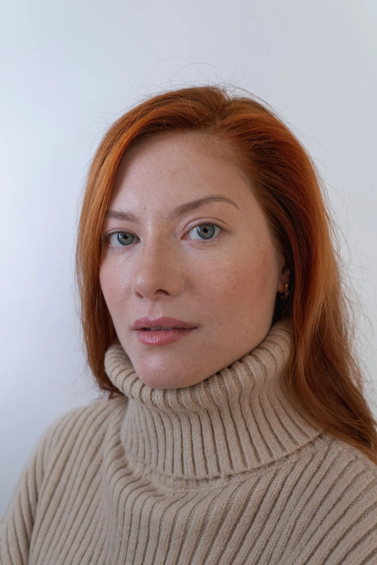 Retrato ilustrativo de uma mulher ruiva com suéter bege; foto de banco sem vínculo com a identidade fictícia